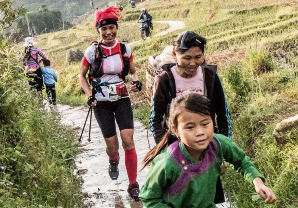 Vietnam marathon trail runners running alongside minorities in sapa rice fields